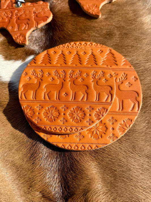 Decorative terracotta coaster with reindeer design on a textured surface