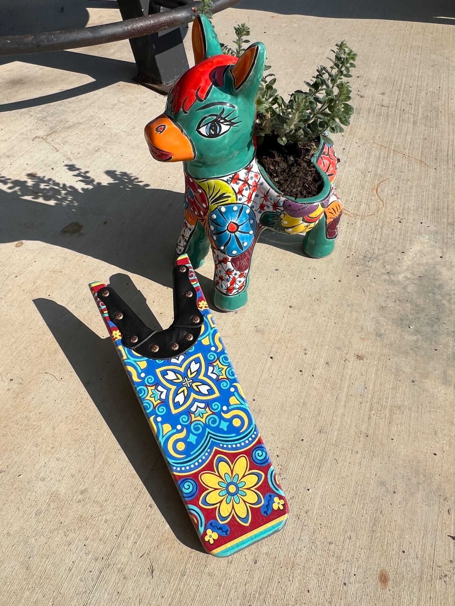 Colorful cat-shaped planter with floral design on a concrete surface