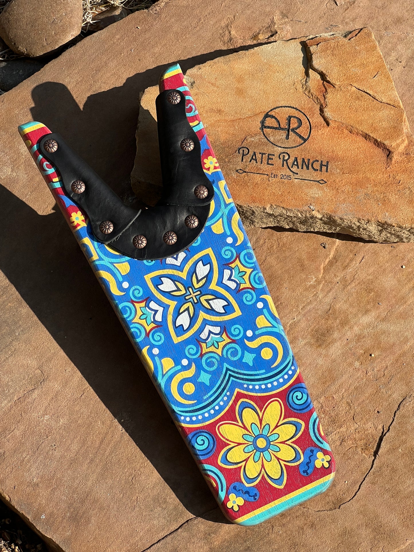 Colorful pocket knife with floral design on a stone surface