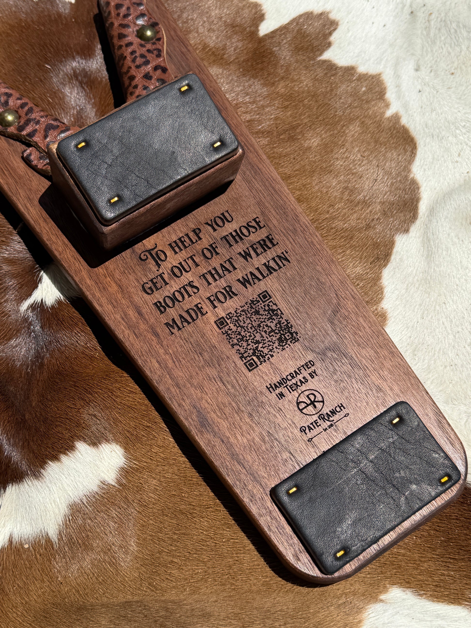 Wooden belt with engraved text and QR code on a brown and white patterned surface