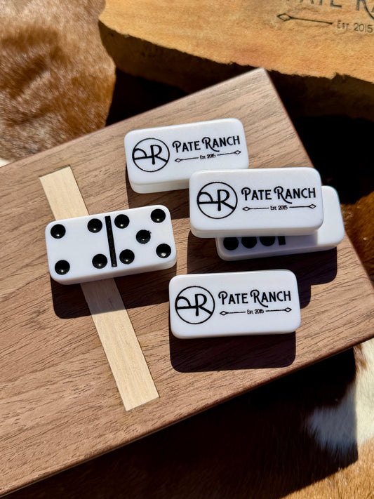 White dominoes with 'Pate Ranch' branding on a wooden surface