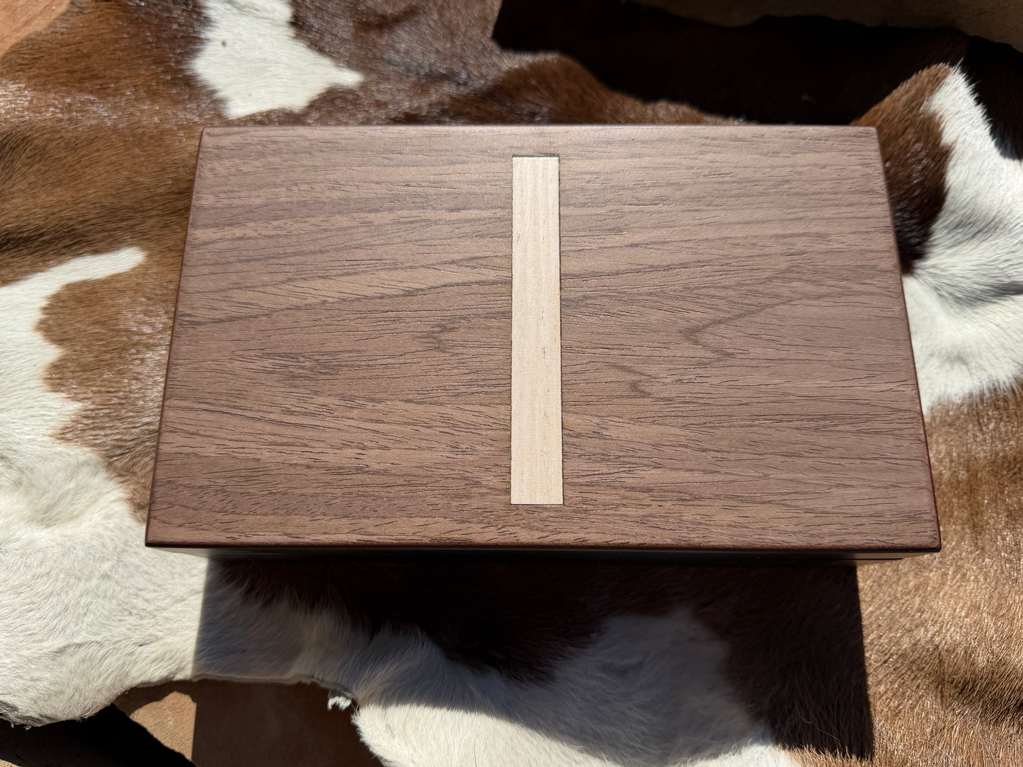 Wooden box with a beige strip on a brown and white fur surface