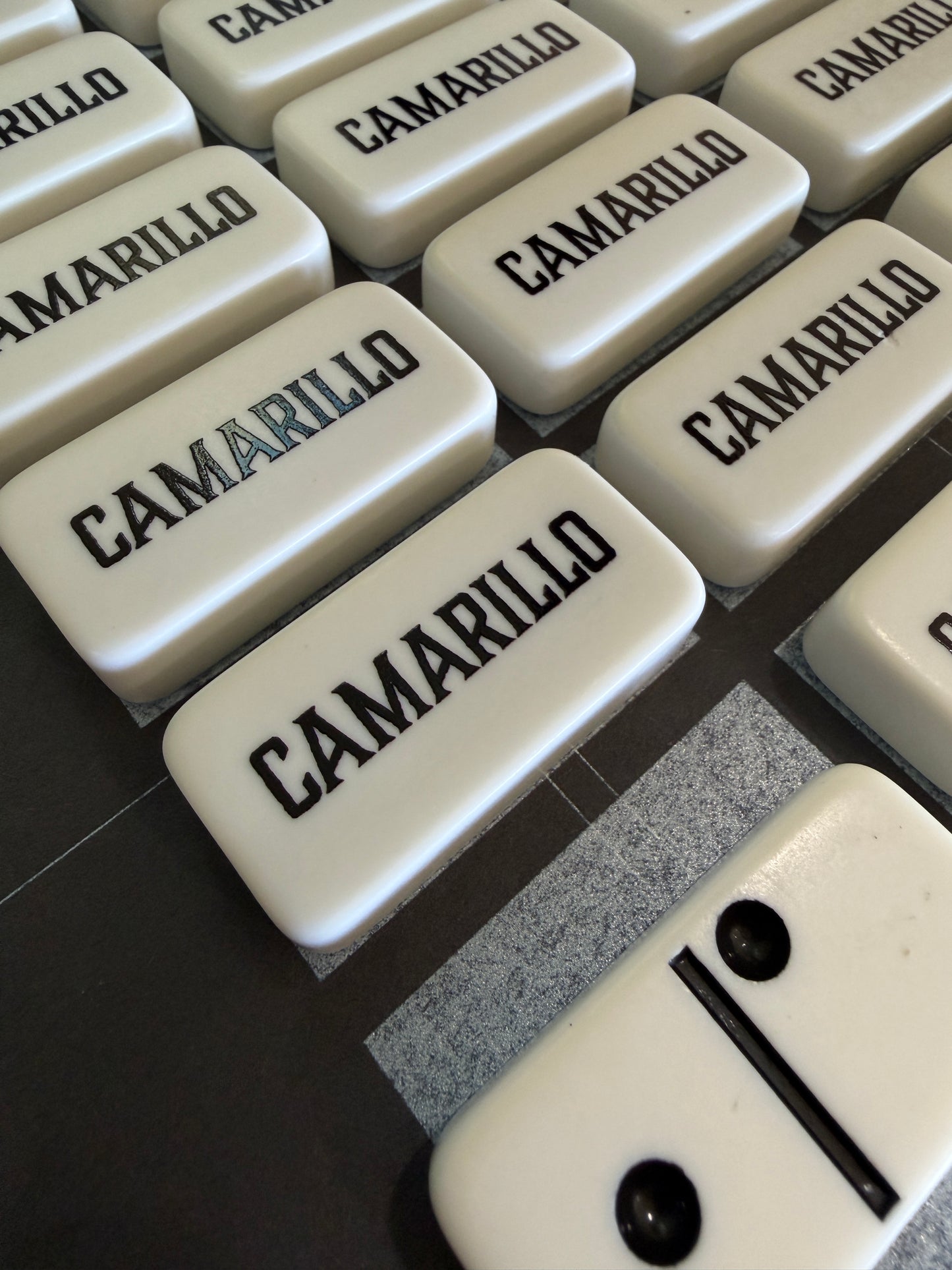 Dominoes with 'Camarillo' branding on a dark surface