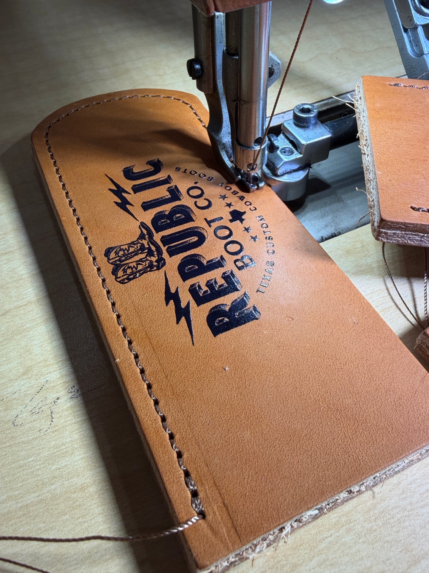 Brown leather product with 'Republic Boot Co' branding being sewn.