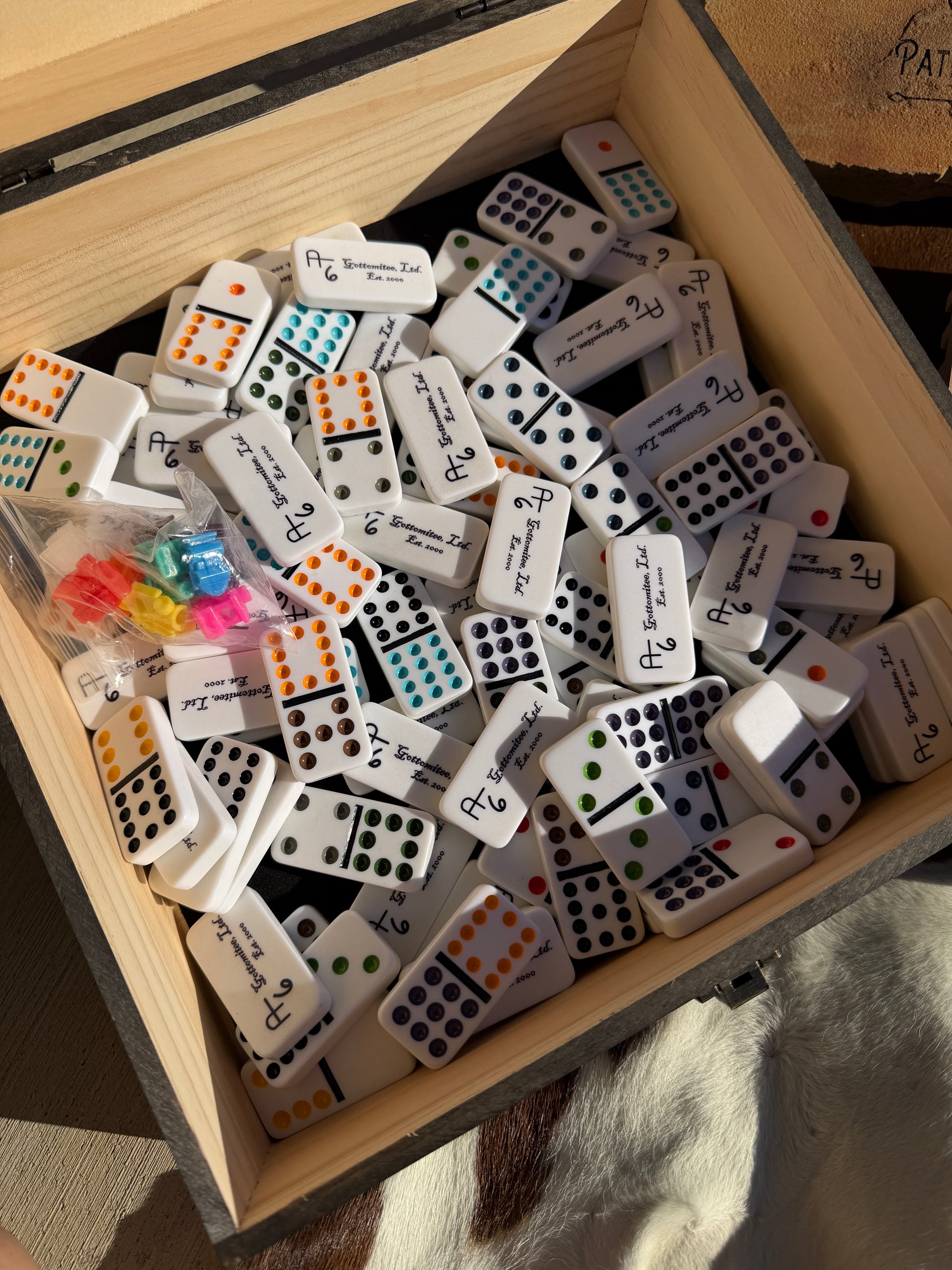 Collection of dominoes in a wooden box with various numbers and symbols.