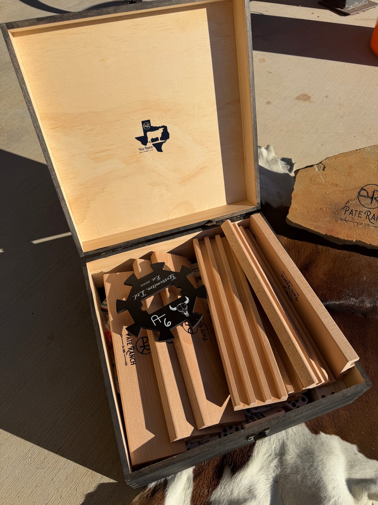 Open wooden box with branded items on a concrete surface