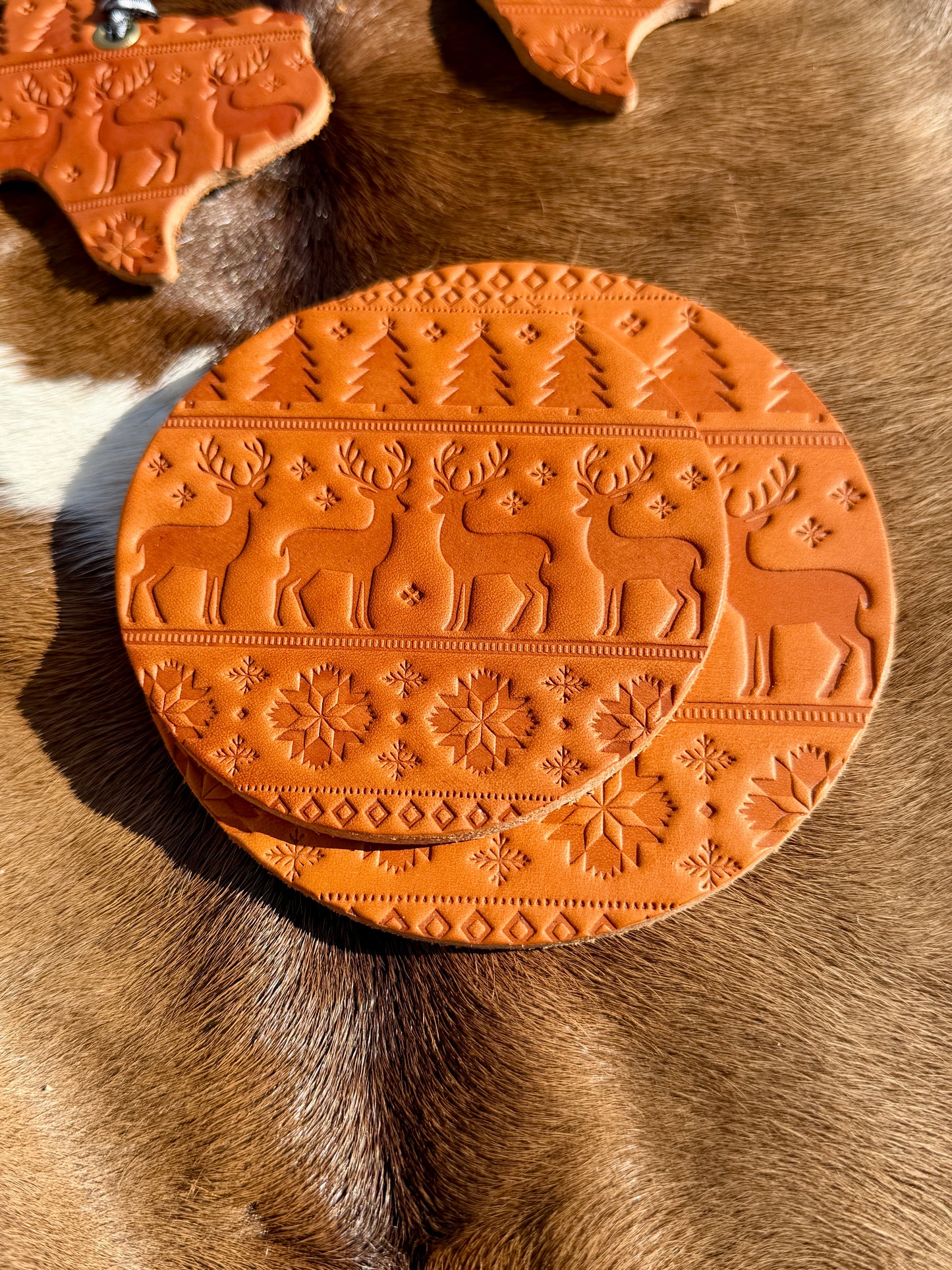 Decorative terracotta coaster with reindeer design on a textured surface