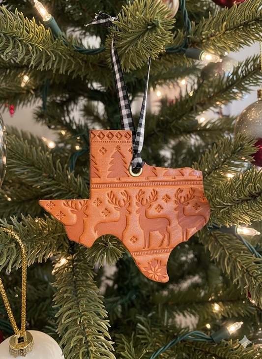 Decorative Texas-shaped ornament on a Christmas tree with lights.