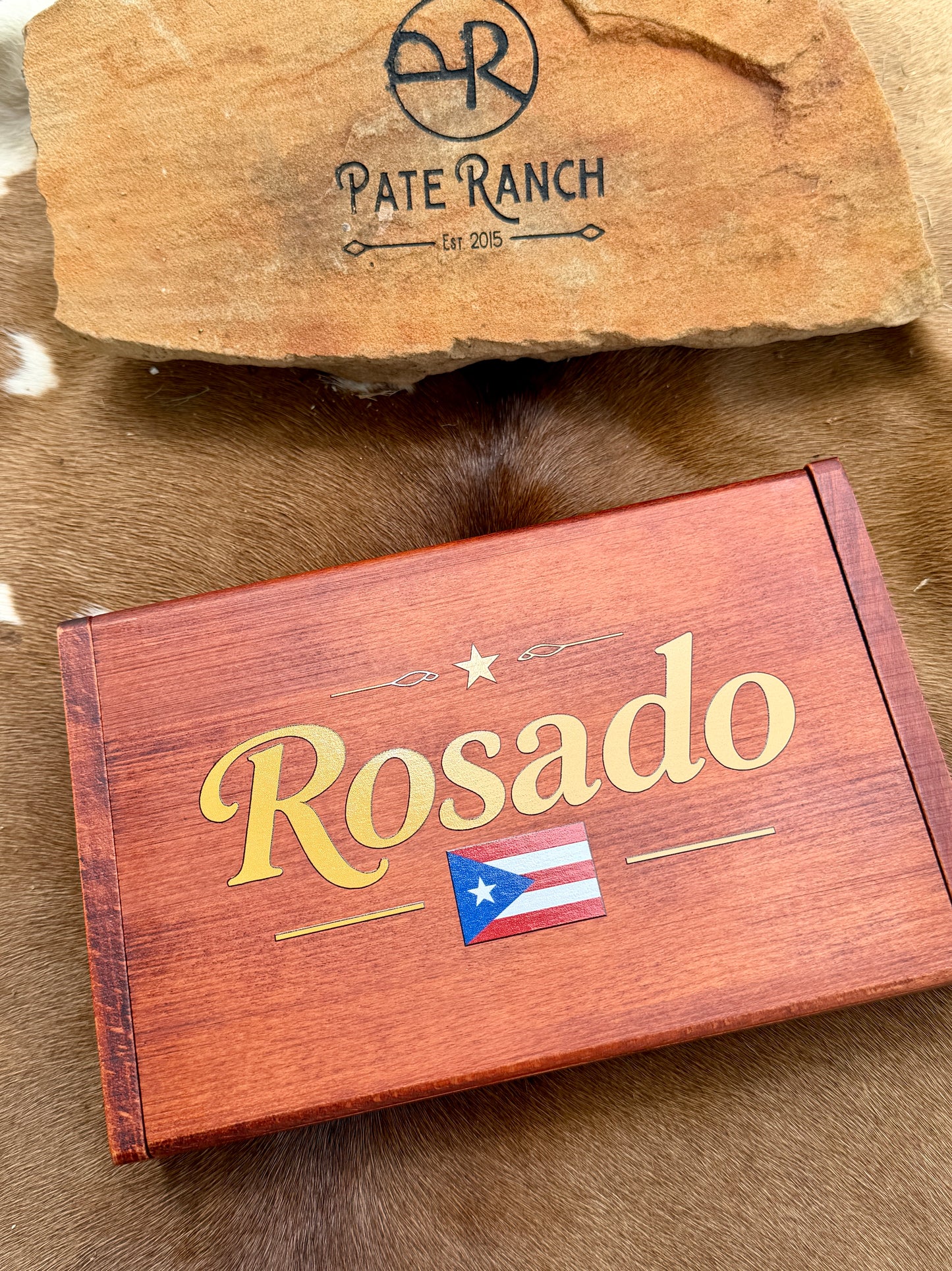 Wooden box with 'Rosado' branding and a Puerto Rican flag on a wooden surface with 'Pate Ranch' logo.