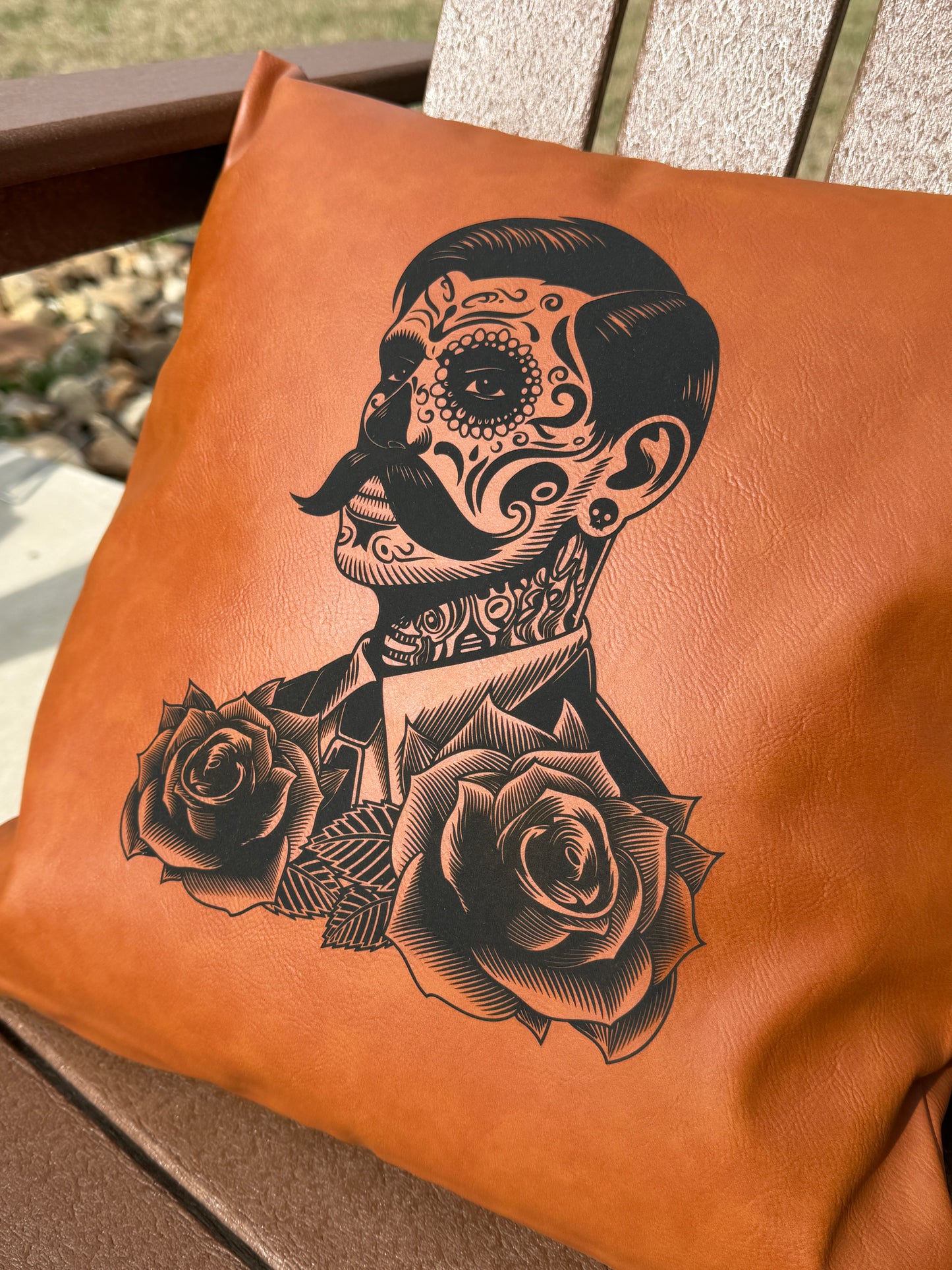 Brown leather bag with black skull and rose design on a wooden surface